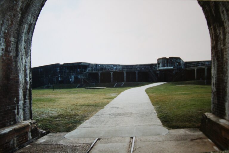 Path through a brick archway leading toward the walls of historic Fort Morgan near Gulf Shores, Alabama