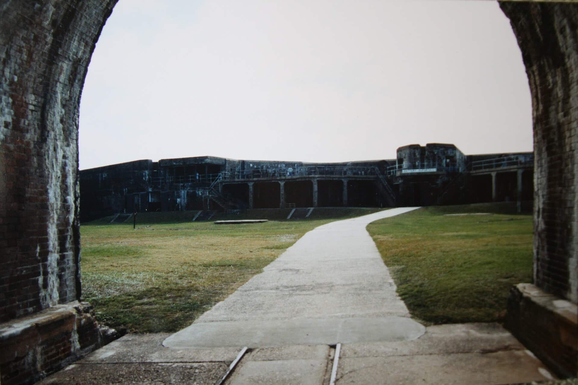 Path through a brick archway leading toward the walls of historic Fort Morgan near Gulf Shores, Alabama
