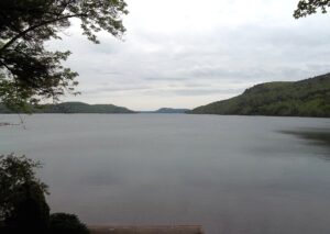 Otsego Lake stretching north from Cooperstown, New York, between wooded hills under a soft grey sky